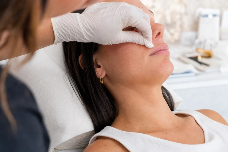 A provider in gloves gently examining the upper lip of a client in a consultation chair