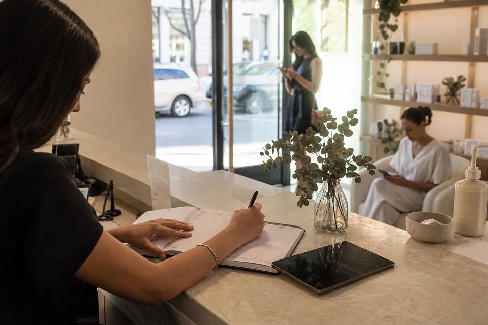 A med spa reception desk with an appointment book, a phone and a tablet seen from the waiting area